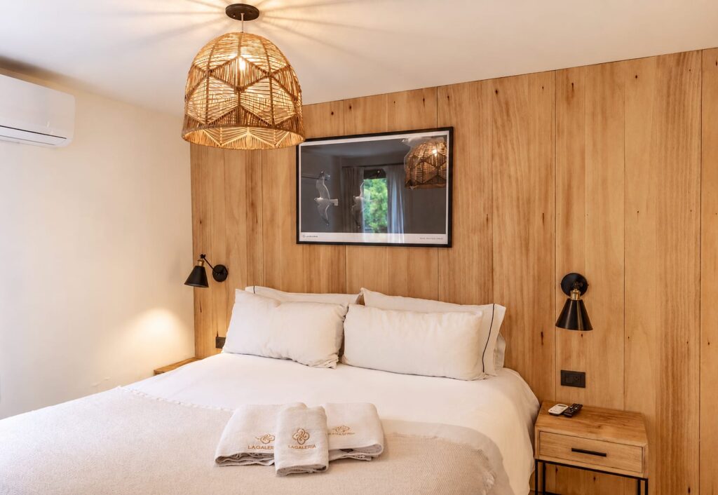 Cama matrimonial de un Deluxe Studio con respaldo de madera y lámpara de fibras