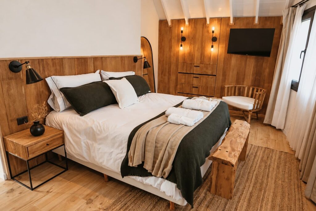 Cama matrimonial de un Deluxe Studio con mantas en tonos verde y arena