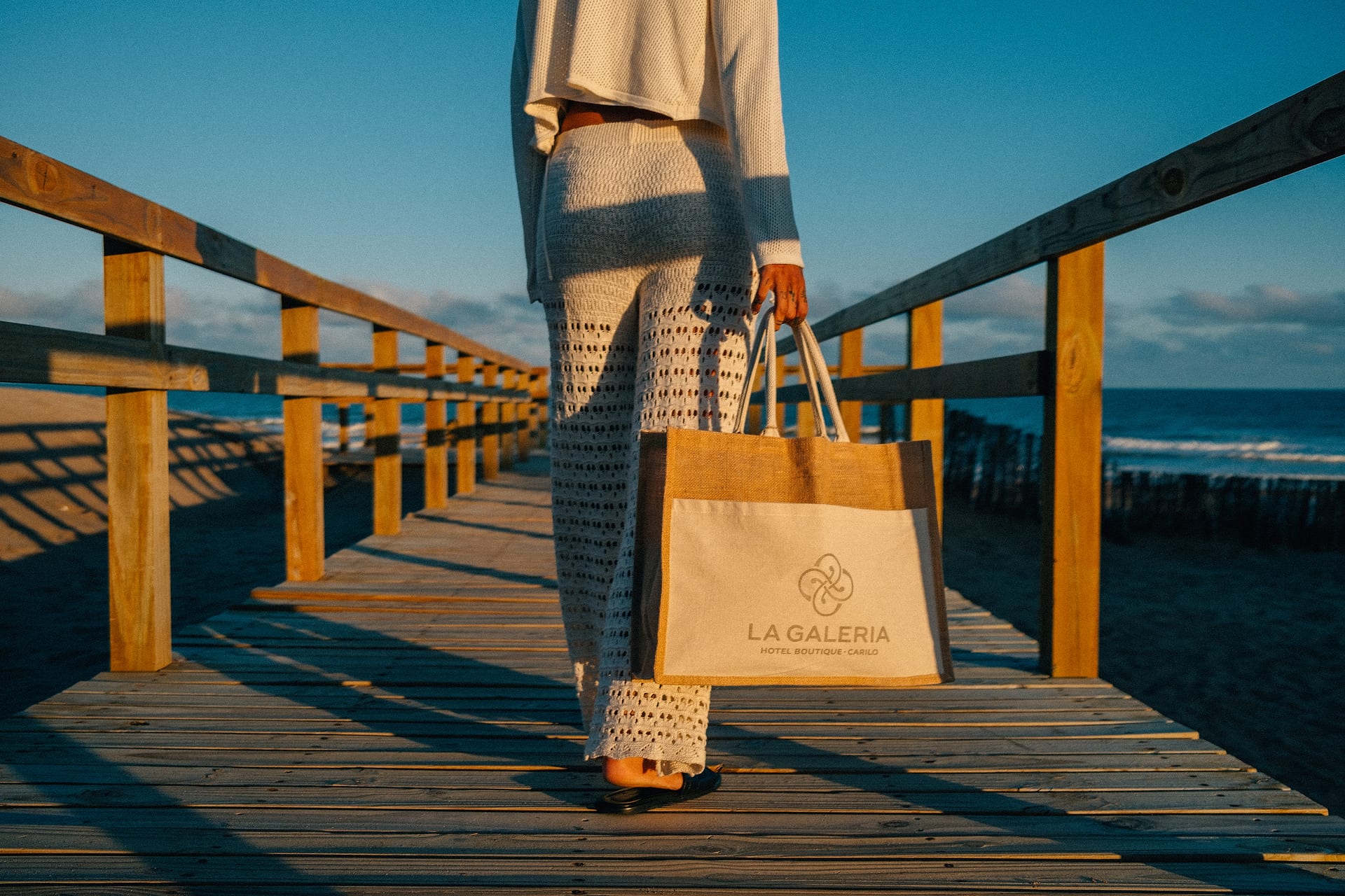 Huésped con el bolso de La Galería en la pasarela de la playa de Cariló